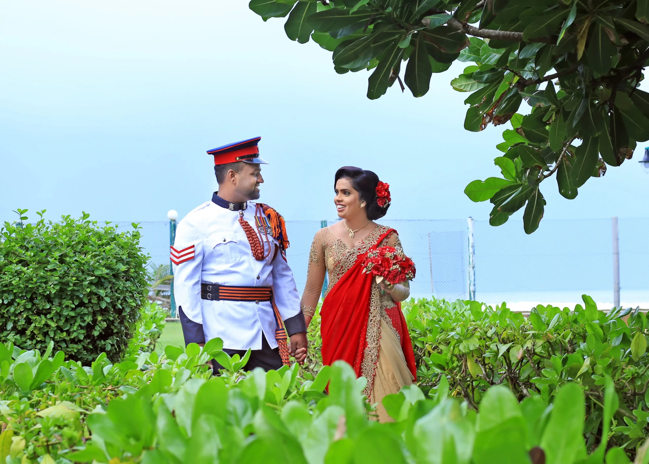 Couple holding hands in lush green natural surroundings.