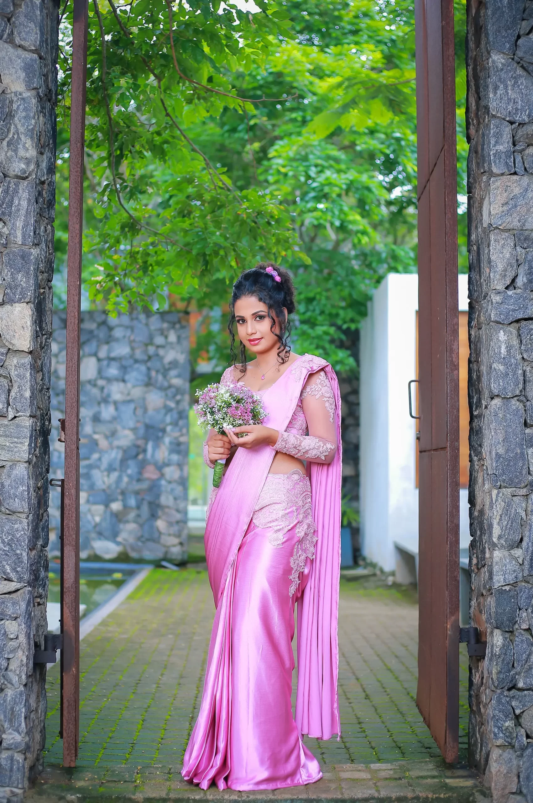 Bride standing confidently with greenery in the background.