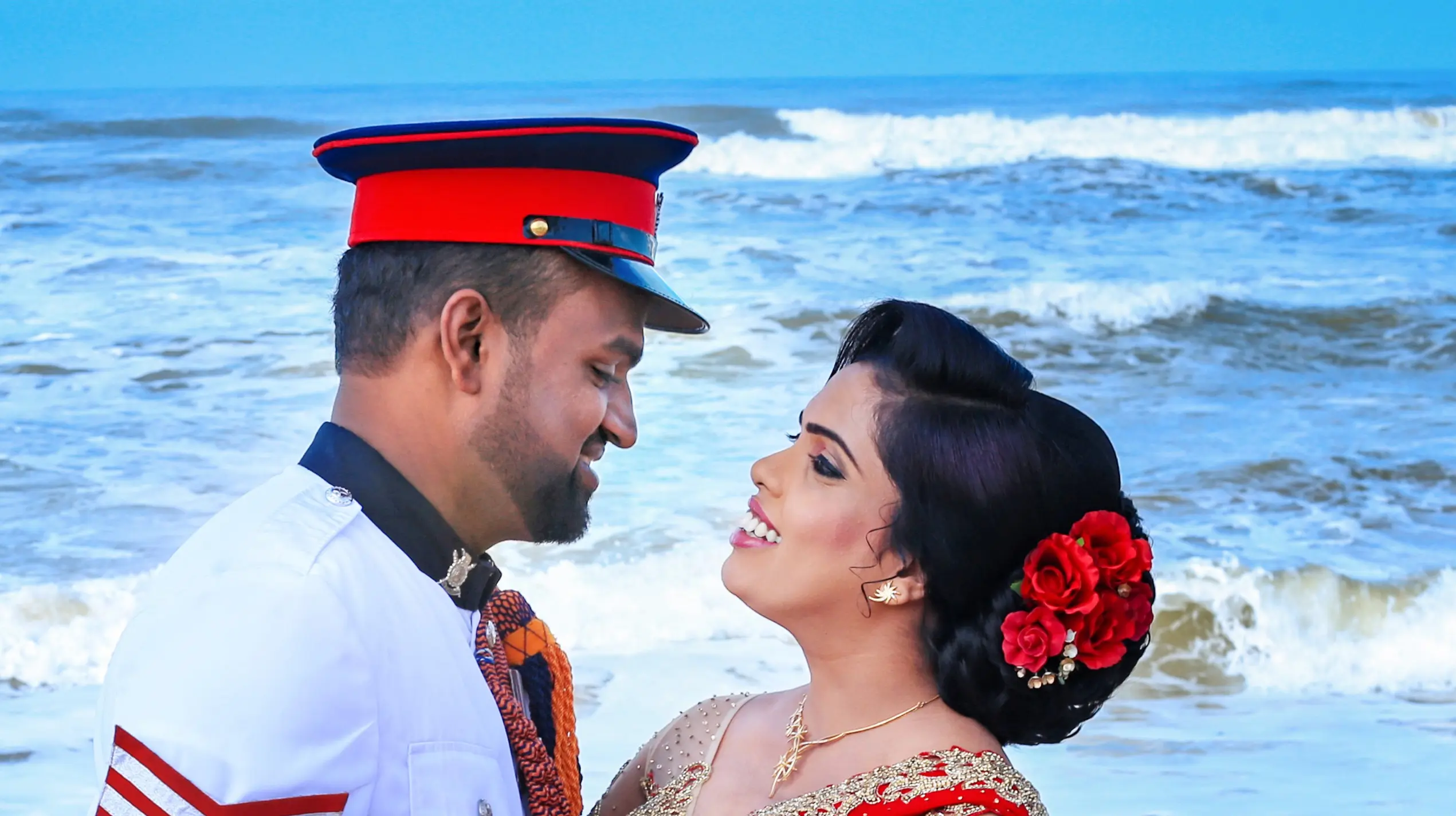 Bride and groom exchanging rings with waves in the background