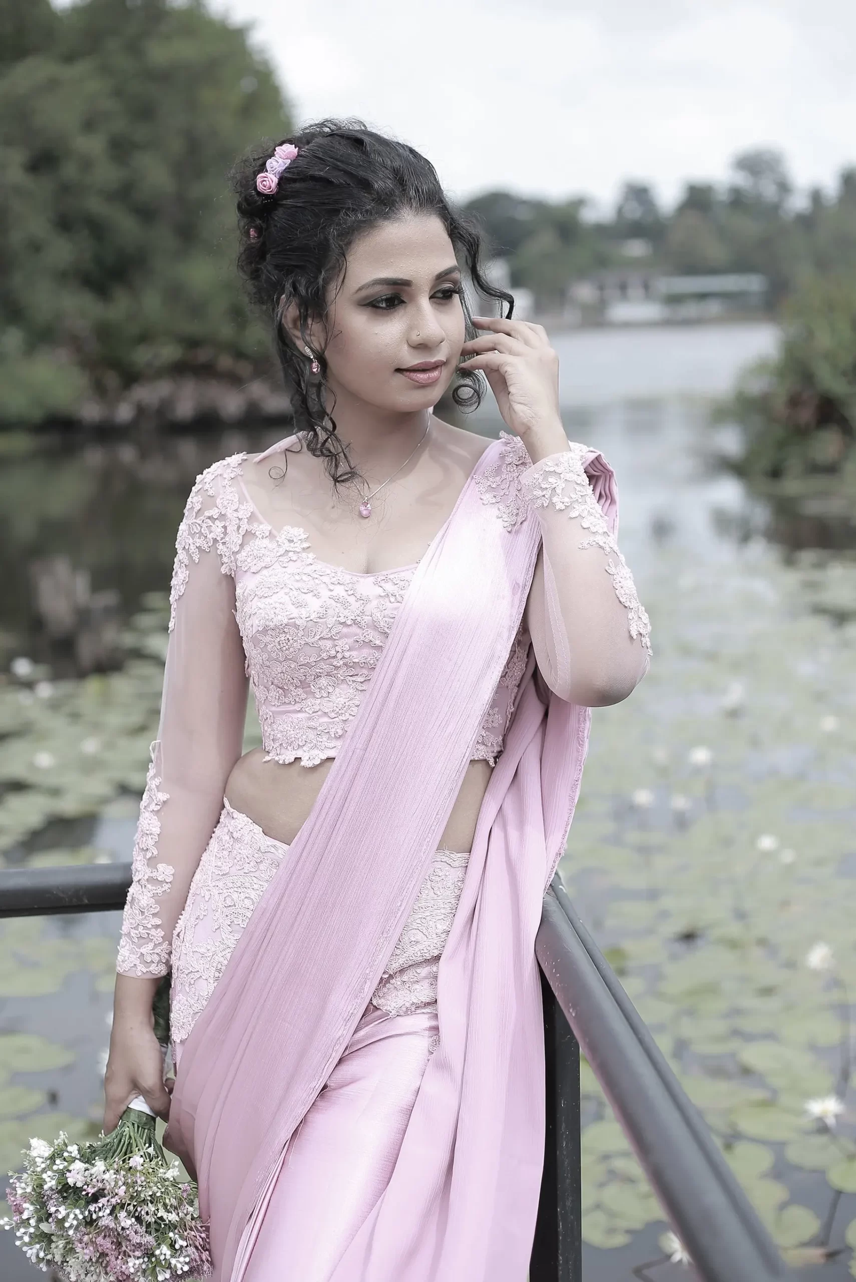 Bride holding her bouquet with a serene expression in a green landscape.