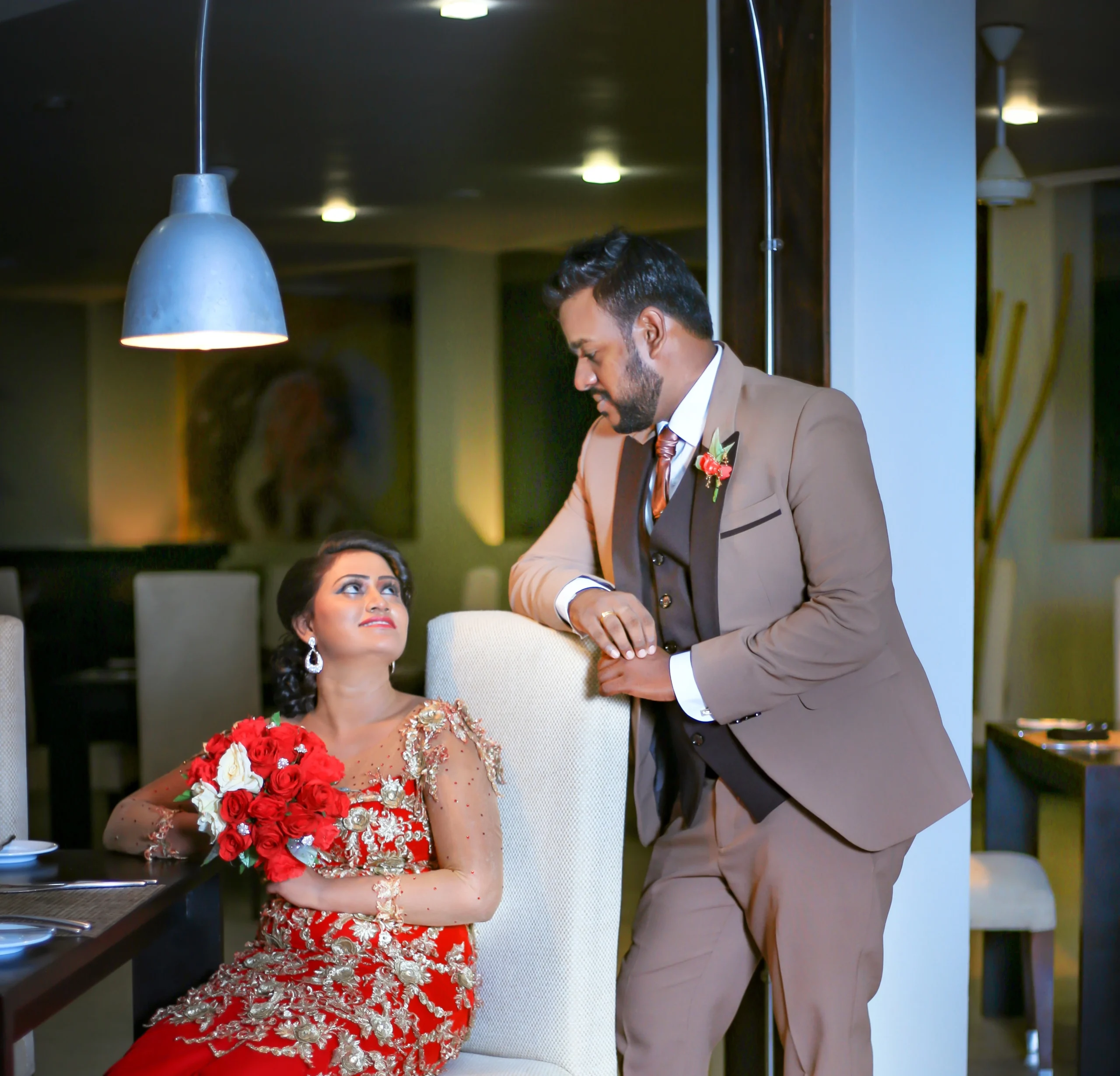 Bride in a red dress holding her bouquet close during an indoor wedding shoot.