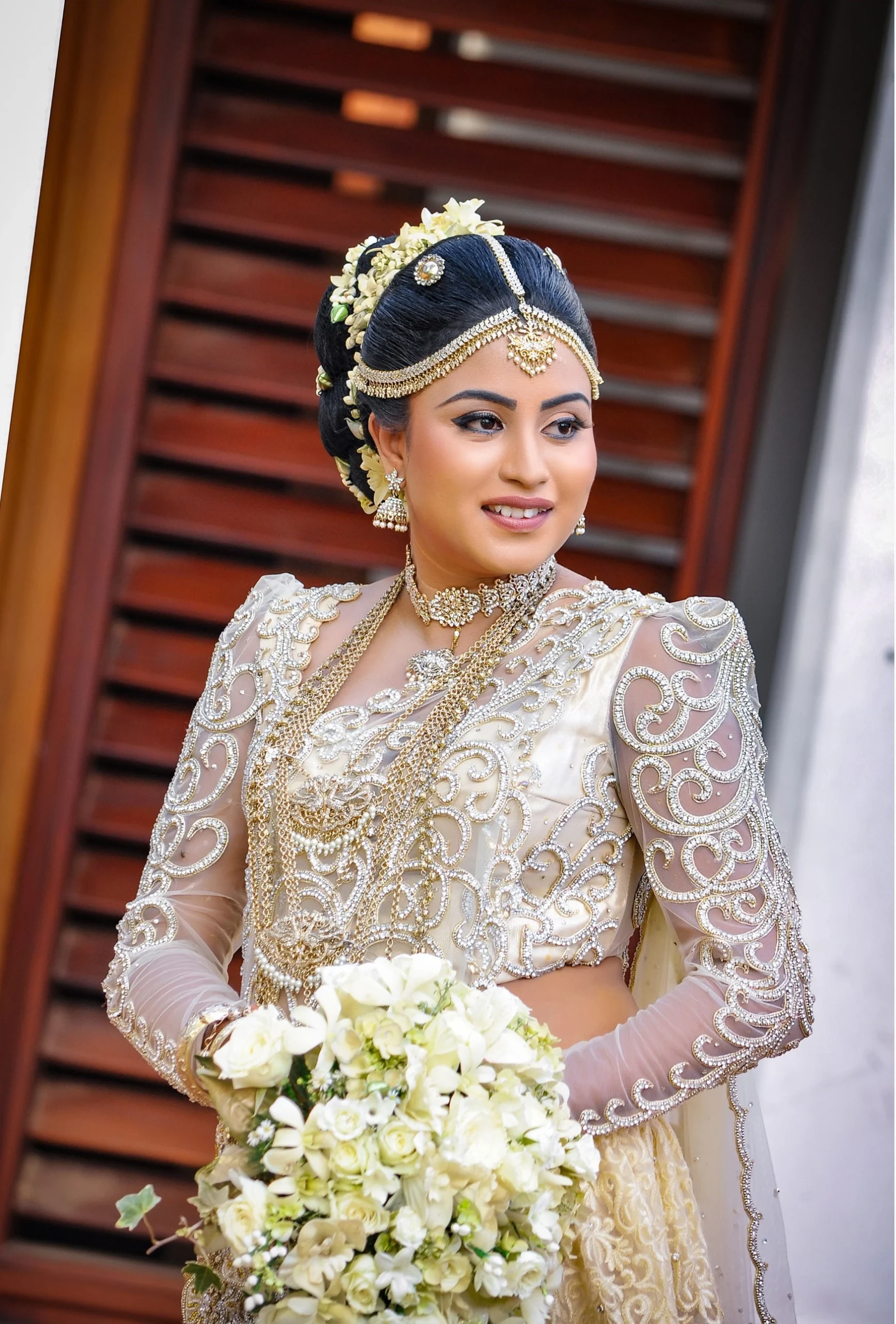 Bride holding her dress while standing on a wooden bridge.