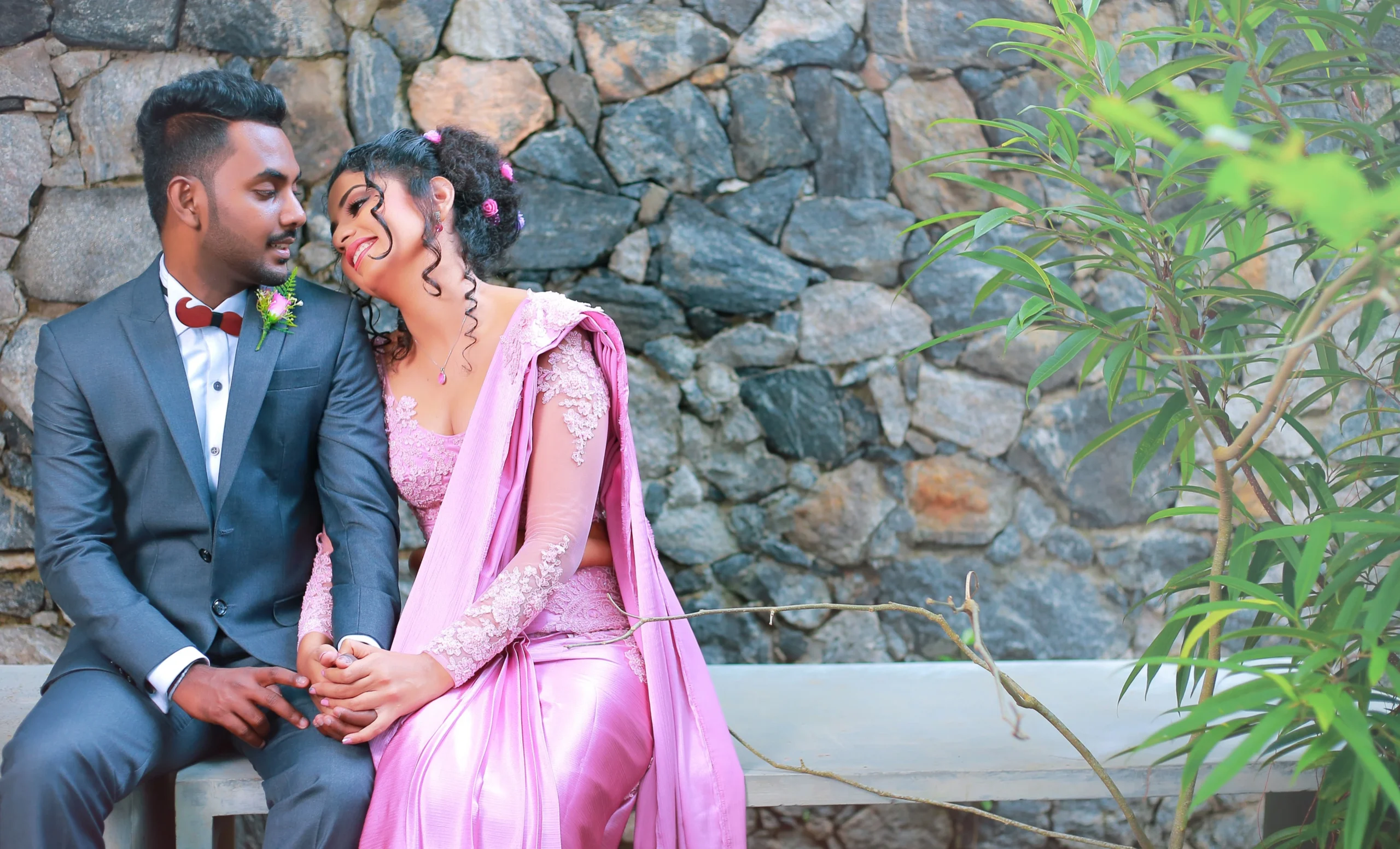 Bride and groom under a wooden arch decorated with greenery